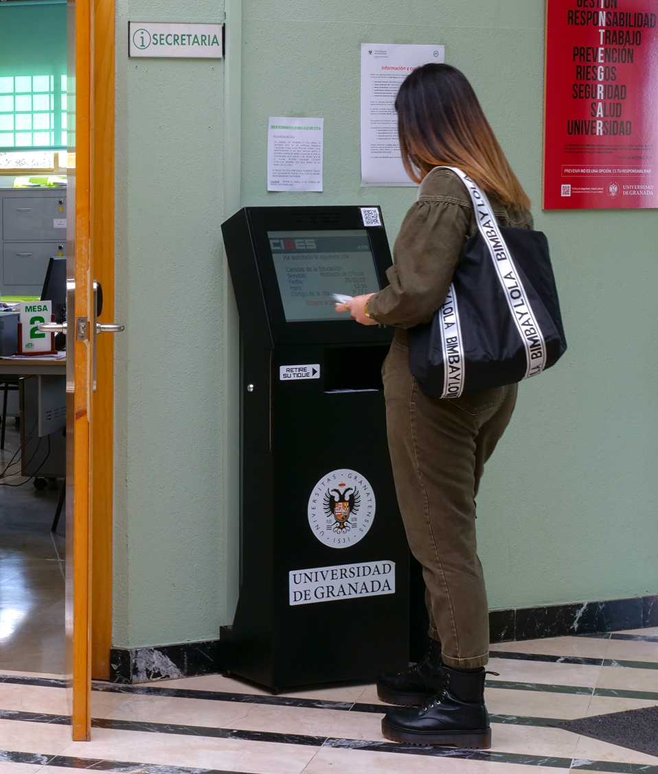 Chica sacando número en máquina de ciges para de entrada a la Secretaría de Ciencias de la Educación