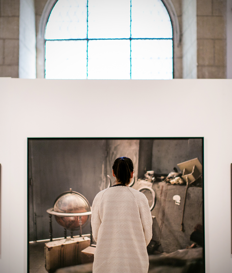 Mujer de espaldas observando cuadros en exposición en crucero del Hospital Real
